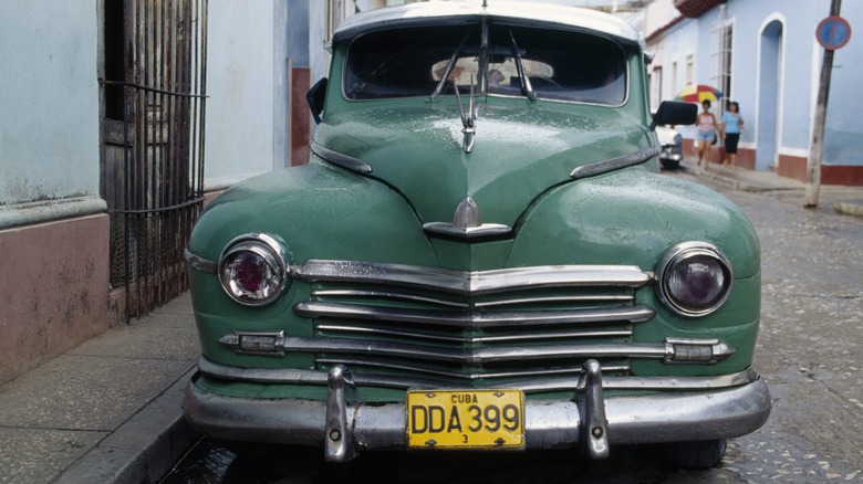 A green vintage car with a front license plate