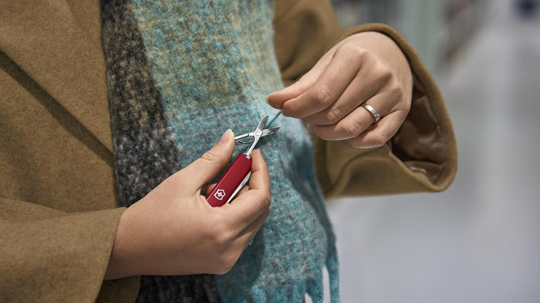 A woman is using the Swiss Army Knife scissors to cut her nails