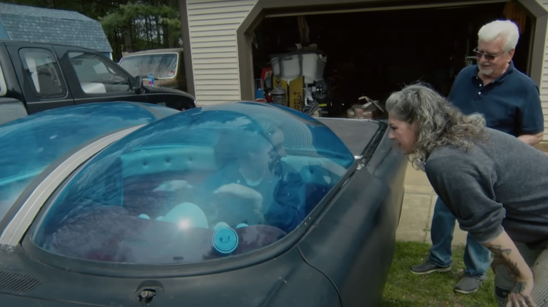 Danielle Colby peers in the window of an Ultimus bubble car at the driver's seat where Mike Wolfe is sitting, while owner Rick Klibenski watches