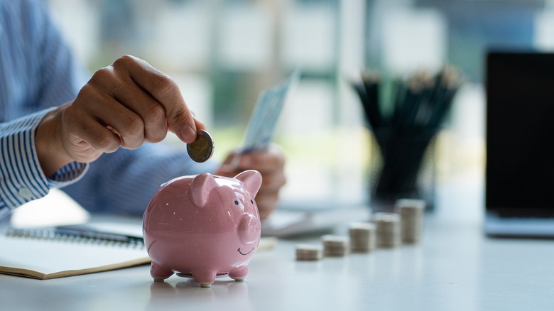 A person putting a coin in the piggy bank