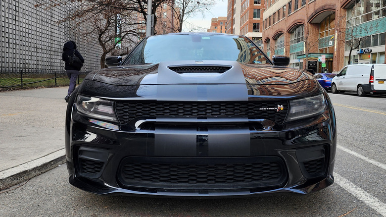 front of black srt hellcat on street