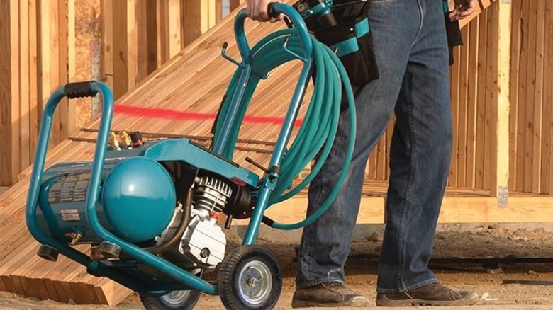 Person dragging an air compressor across the jobsite