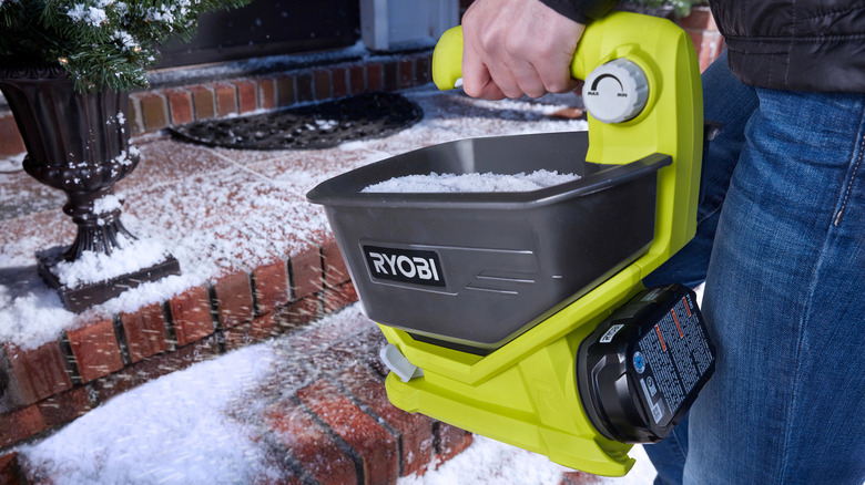 Person using Ryobi power spreader on icy steps