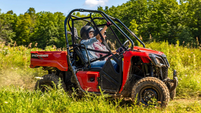 Side angle view of a driver and passenger in a Honda Pioneer 520