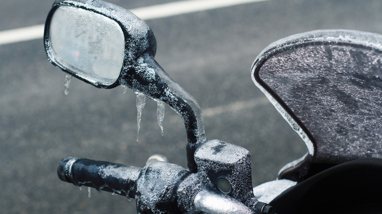 An ice-covered rearview mirror of a motorcycle.