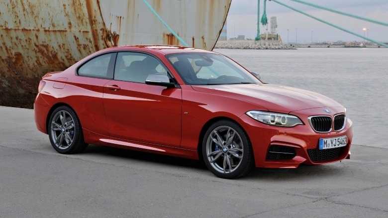 2014 BMW 2 Series parked in a dock area with a docked ship in the background