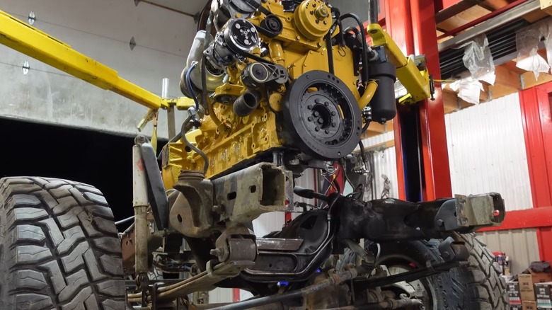 A yellow Cat engine being fitted onto a truck