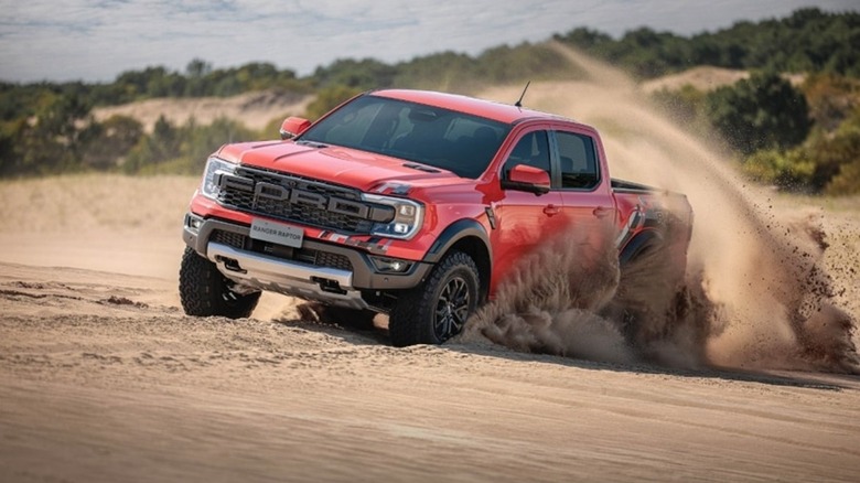 A red Ford Ranger Raptor driven in sand.