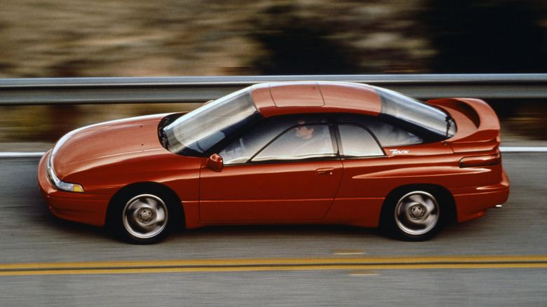 A burnt orange Subaru SVX driving on a mountain road