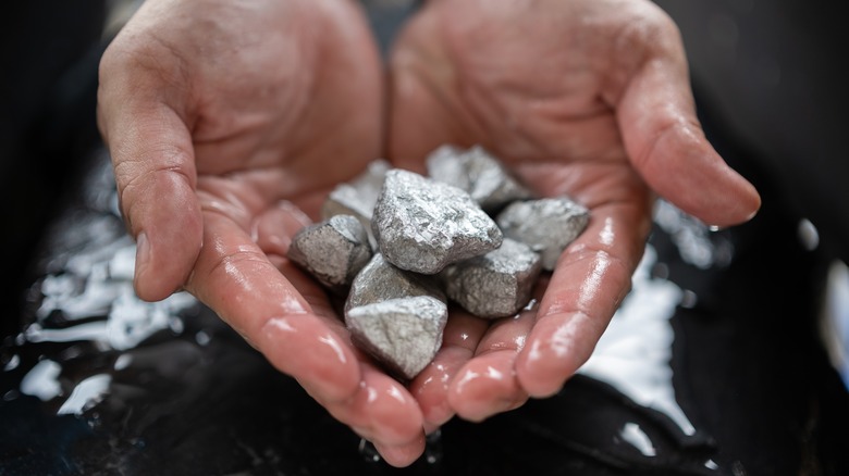 Hands holding platinum in its raw state.