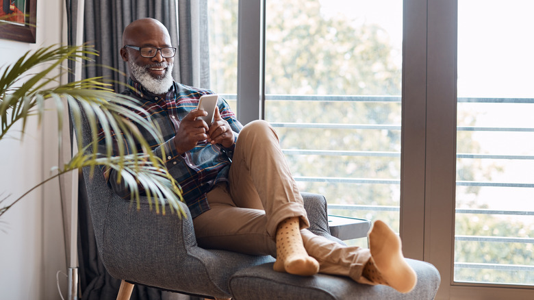 gray haired person sitting smartphone