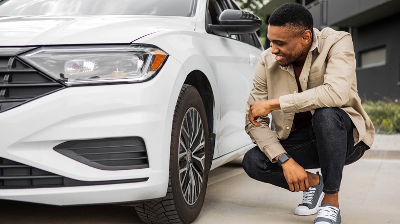 Man crouched near white car