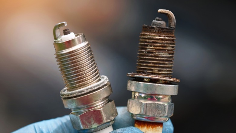 person holding one new and one old spark plug