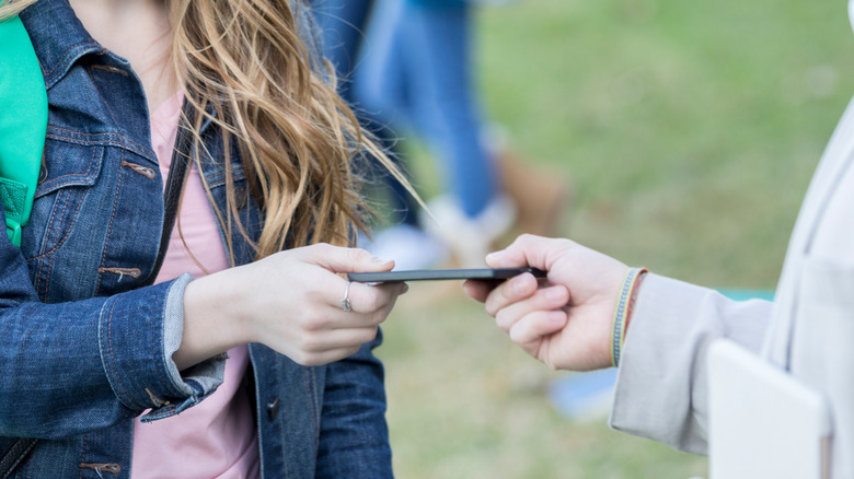 person handing phone to another