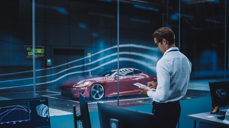 Man standing in front of wind tunnel with a car inside