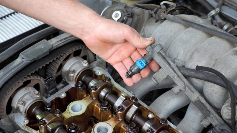 a mechanic putting a fuel injection system into an engine