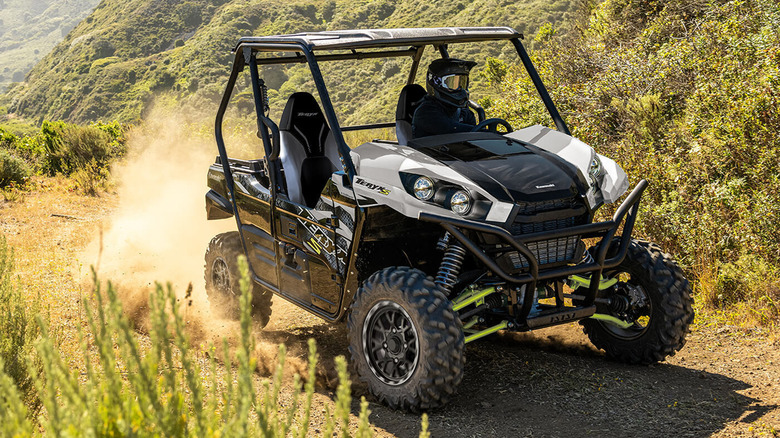 white and black Kawasaki Teryx side-by-side riding on dirt road on mountain