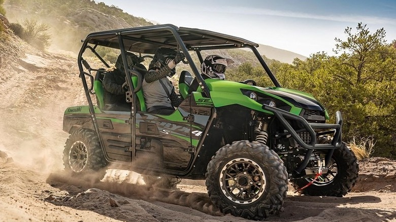 Green Kawasaki Teryx 4 parked on dirt road in mountains