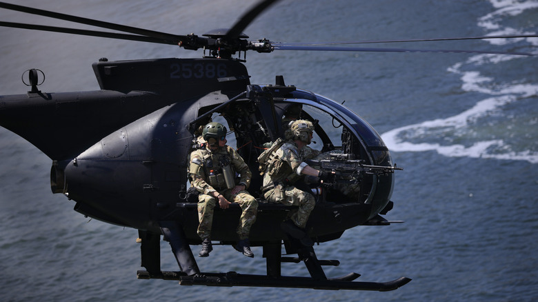 Soldiers flying in helicopter over water