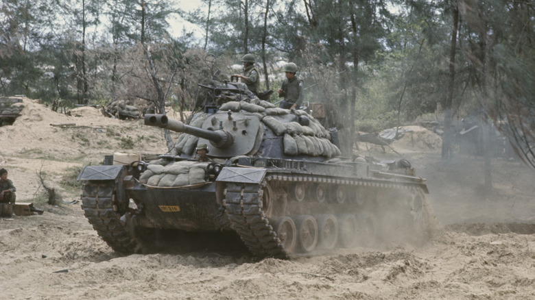 M48 tank driving through woodlands