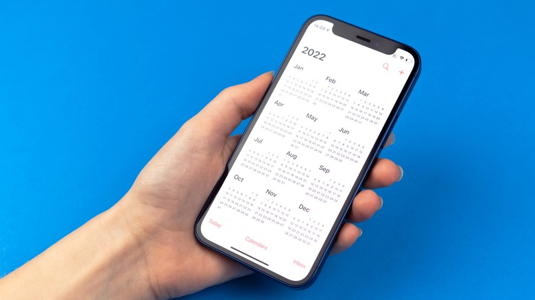 person holding iPhone with Calendar app open