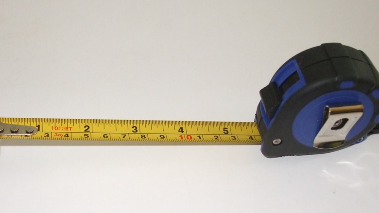 A tape measure with the tape extended nearly six inches.