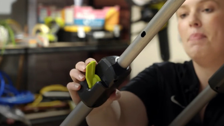 Woman snapping back the height adjustment clamps on Ryobi push mower