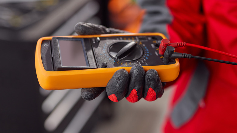 Hand holding multimeter with leads plugged in