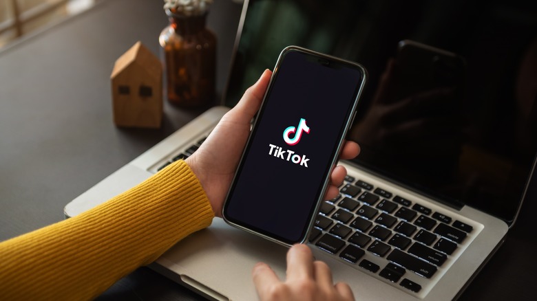 TikTok on iPhone in front of MacBook