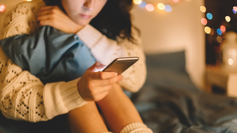 woman using phone in bed