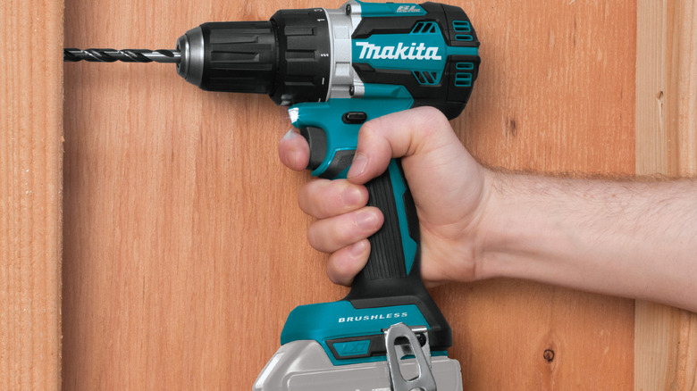 Person using Makita drill to create a hole