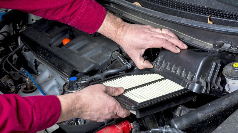 person replacing engine air filter