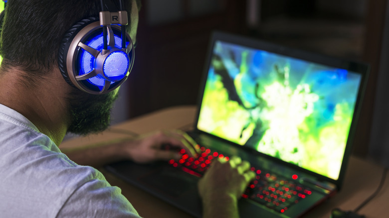 Man wearing headphones and gaming on laptop