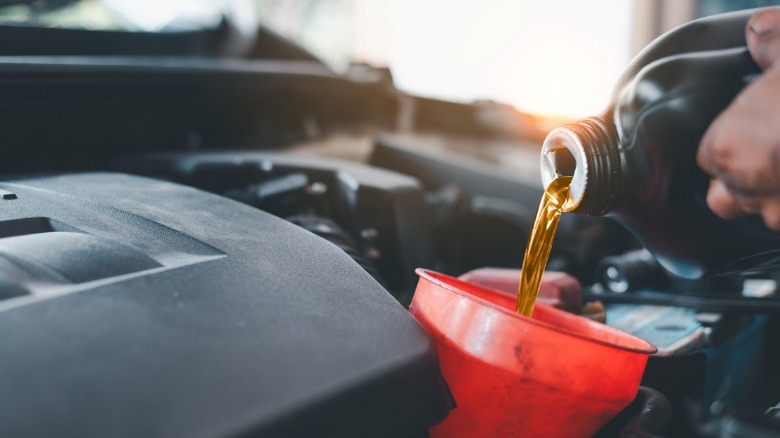 A person pouring oil into an engine fill port