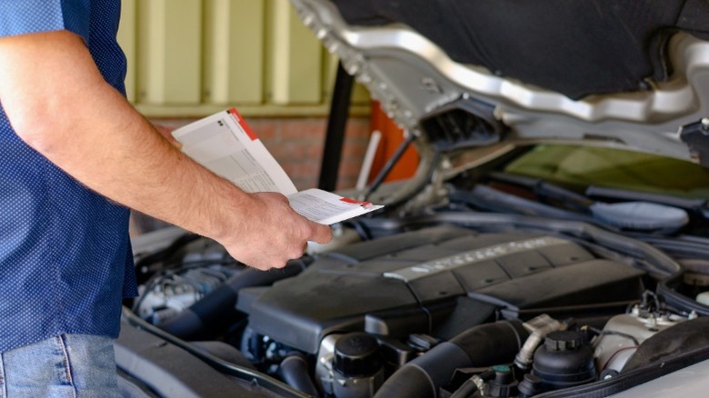 A person using a car repair manual to determine the type of transmission their vehicle has