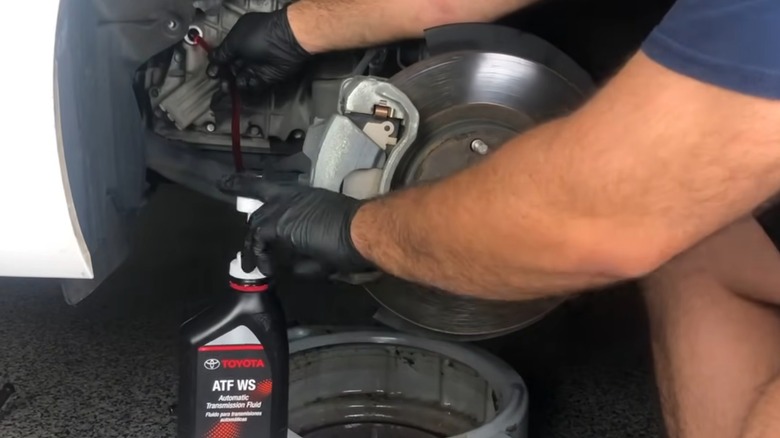 A person using a pump to refill their sealed transmission with fluid