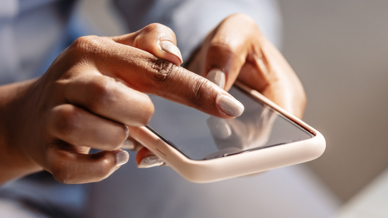 hands holding smartphone, touching screen with one finger