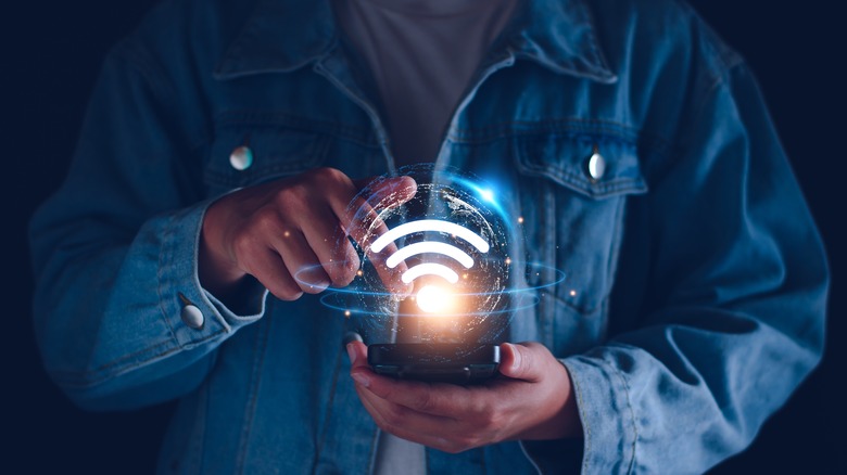 man holding phone with Wi-Fi logo on it