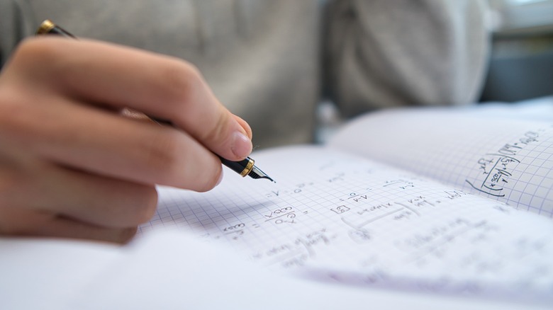 hand with pen over math homework