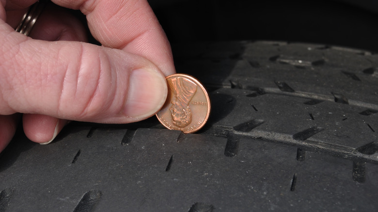 Hand inserting a penny on tire groove