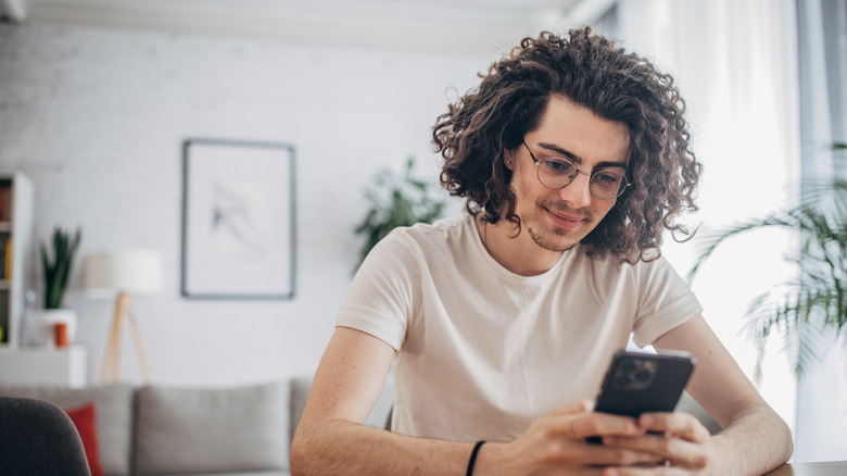 young man using iPhone in living room