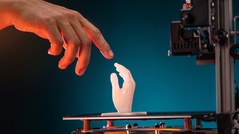 hand reaching out to small 3D printed hand