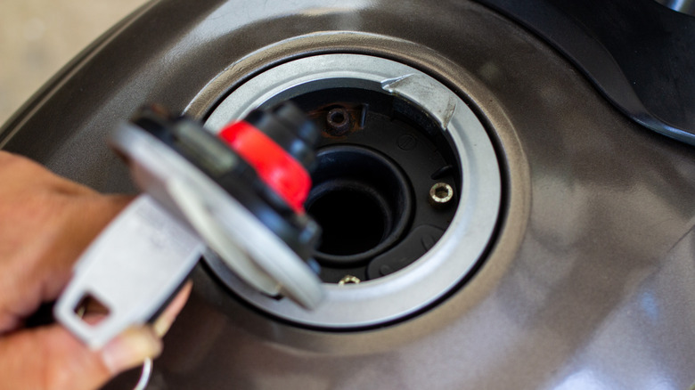 Person opening motorcycle gas tank