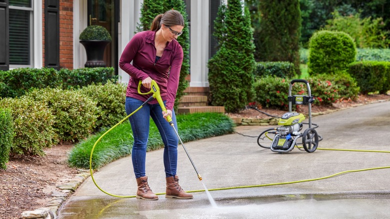 Woman using Ryobi electric pressure washer