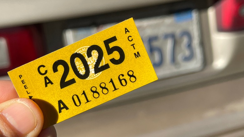 A person holds a California DMV sticker