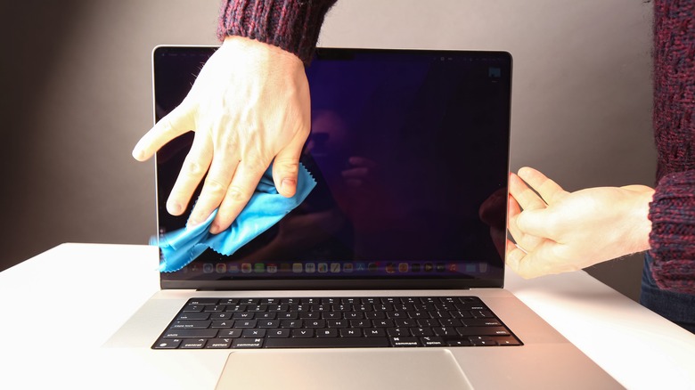 man wiping MacBook screen 