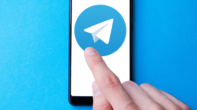 Touching Telegram logo on smartphone screen