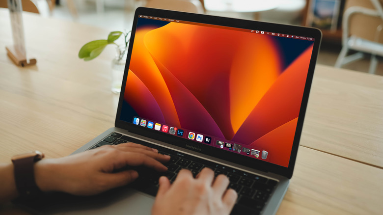 A man using MacBook Pro on a wooden desk