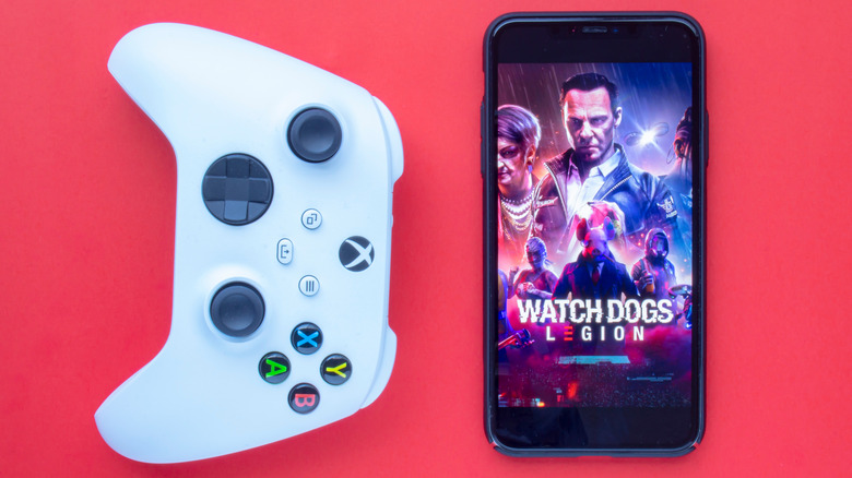 white Xbox controller next to iPhone with Watch Dogs Legion wallpaper