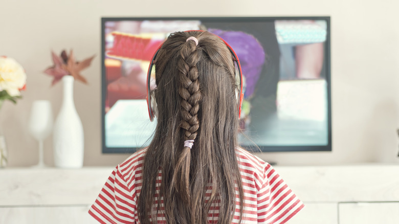 A girl watching TV with headphones on